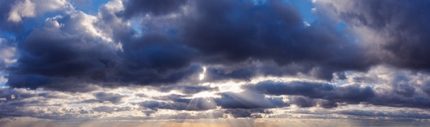 I raggi del sole brillano attraverso le nuvole scure di pioggia nel cielo.