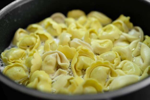 I ravioli saporiti sono bolliti in una cucina italiana fatta in casa di una casseruola nera