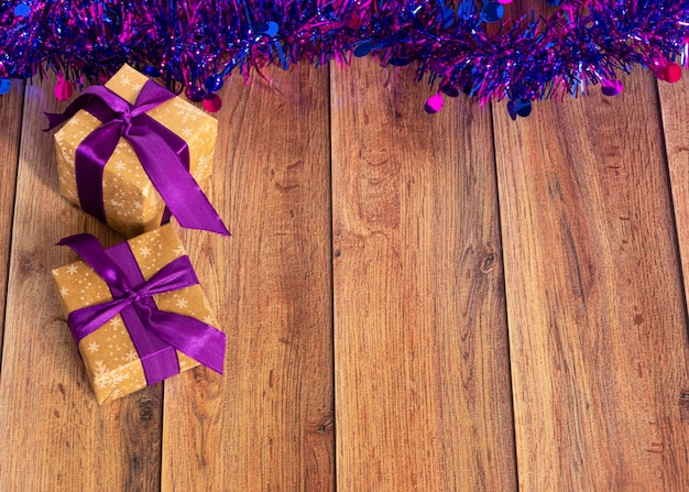I regali sono confezionati in carta kraft e legati con un nastro di raso con orpelli viola su uno sfondo di legno