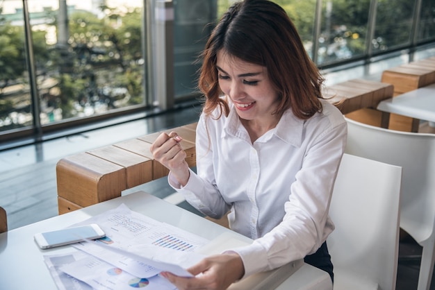 I ritratti di bella donna asiatica sembrano allegri e la fiducia è seduta e sente il successo con il lavoro.