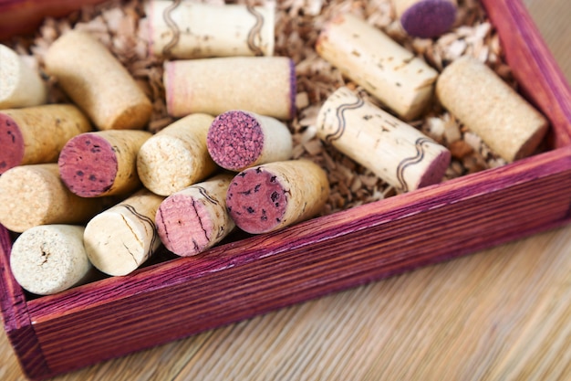 I tappi usati si chiudono su in scatola di legno rossa. Vecchi tappi di vino rosso e bianco su legno naturale.