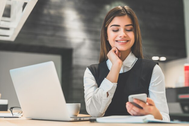 I telefoni della bella donna d'affari vicino al laptop