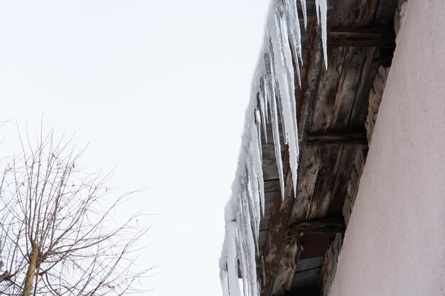 I tetti degli edifici sono ricoperti di neve e ghiaccio dopo una grande nevicata Enormi ghiaccioli pendono dalle facciate degli edifici La caduta dei ghiaccioli rappresenta un pericolo per la vita delle persone