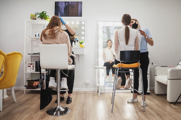 I truccatori compongono le giovani donne nel salone di bellezza. Servizio clienti in sala interna