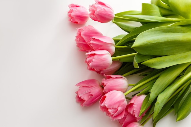 i tulipani rosa giacciono su un tavolo bianco