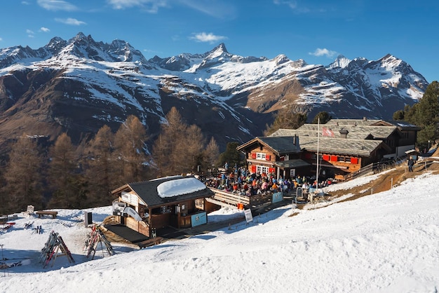 I turisti al di fuori del caffè presso la stazione sciistica con bellissime montagne innevate
