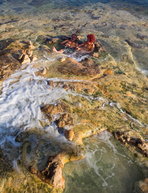 I turisti fanno bagni curativi naturali alle sorgenti termali con acqua minerale in una località termale in Grecia