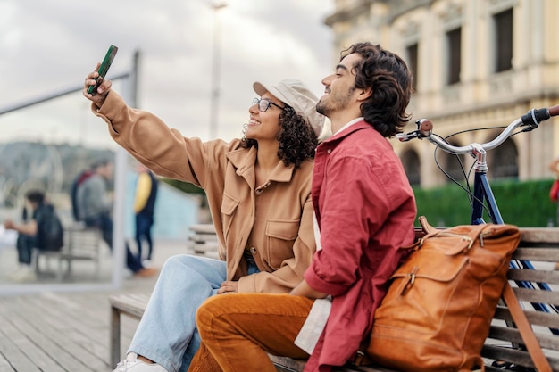 I turisti scattano selfie seduti su una panchina del molo della città durante le loro vacanze in Spagna