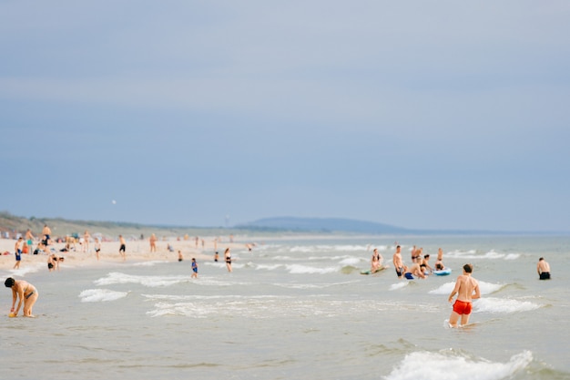 I turisti si rilassano nel mare e sulla spiaggia sabbiosa