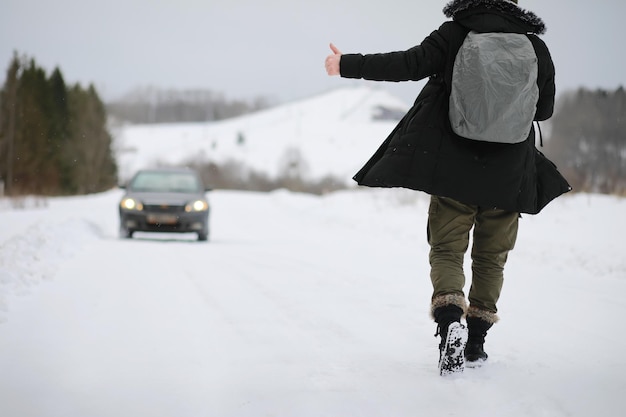 I turisti viaggiano attraverso il paese innevato. Lungo la strada, cammina e fai l'autostop.