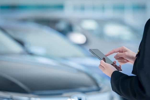 I venditori di auto da donna usano smartphone mobili negli showroom di automobili