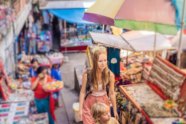 I viaggiatori di mamma e figlio scelgono souvenir nel mercato di Ubud a Bali, in Indonesia