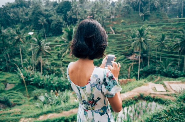 I viaggiatori solitari femminili asiatici usano lo smartphone prendono la foto Tegalalang Rice Terrace, Ubud, Bali, Indonesia