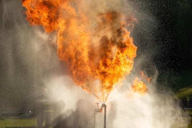 I vigili del fuoco e la formazione di soccorso I pompieri spruzzano acqua ad alta pressione sul fuoco Lo sfondo della fiamma del fuoco in fiamme