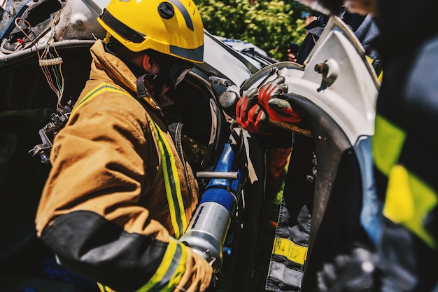 I vigili del fuoco si accovacciano vicino all'auto incendiata e cercano di capovolgerla.