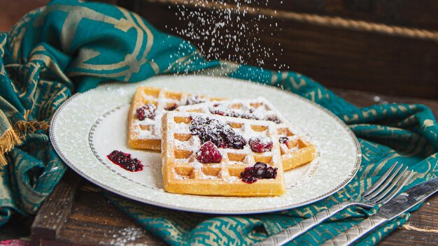 I waffle belgi con frutti di bosco vengono versati con marmellata