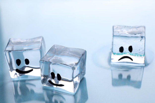 Ice cubes with drawn faces on light background closeup Concept of jealousy