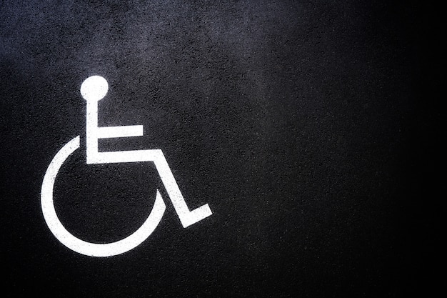 Icona di persone disabili o simbolo di handicap sul parcheggio.