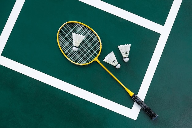 Idea concettuale sportiva competitiva con racchette da badminton e volano sul campo da badminton verde