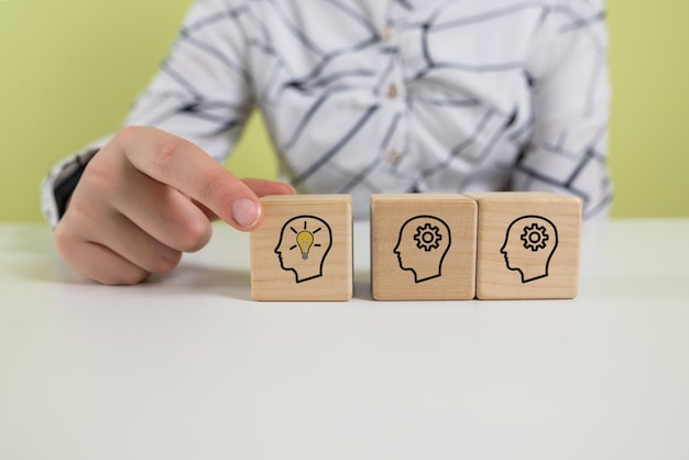 Idea creativa e concetto di innovazione La mano seleziona il blocco cubo di legno con il simbolo della testa umana e l'icona della lampadina