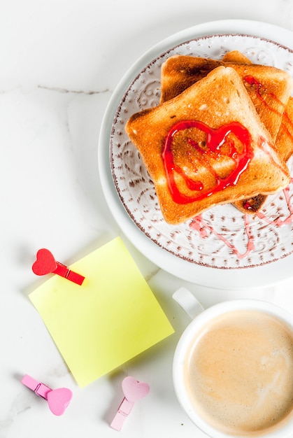 Idea di colazione di San Valentino con una tazza di caffè, pane tostato con marmellata di fragole rossa