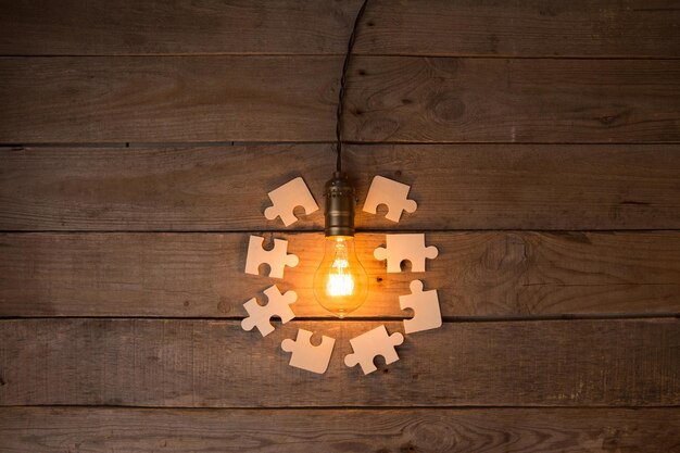 Idea e concetto aziendale di lavoro di squadra lampadina a incandescenza vintage e puzzle sullo sfondo di legno
