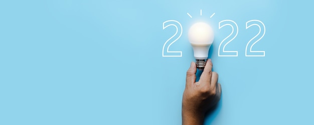 Idea e creatività nel 2022, lampadina con numero di capodanno su sfondo blu