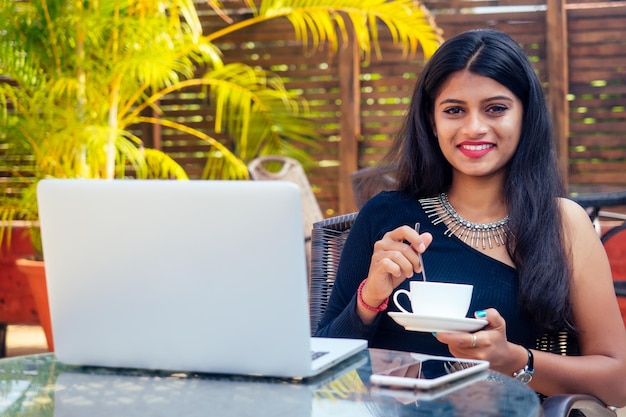 Idea per la pausa caffè Giovane donna d'affari indiana che utilizza un computer tablet nel bar giardino estivo