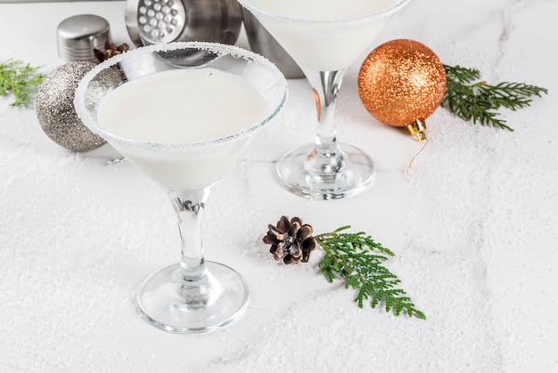 Idee e ricette per drink di Natale. Cocktail Martini al fiocco di neve al cioccolato bianco, sul tavolo di marmo bianco con decorazioni natalizie,