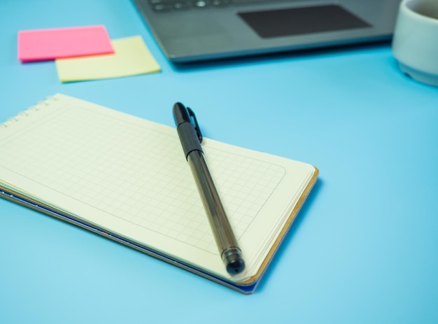 Idee per la scrivania dell'ufficio aziendale vista dall'alto con caffè portatile e blocco note vuoto su sfondo blu spazio copia