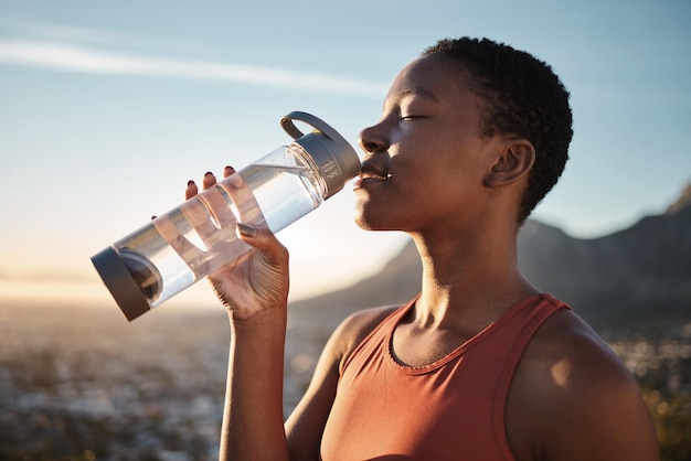 Idratazione dell'acqua e donna di colore che corre nella natura riposo fitness e salute per l'esercizio in Turchia Pausa energetica e allenamento Acqua potabile del corridore africano per la disintossicazione del corpo durante un allenamento all'aperto