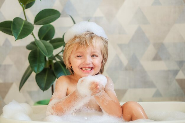 Igiene dei bambini. Il bambino si bagna in un grande bagno. Felice ragazzo carino 4-5 anni con schiuma tra i capelli.