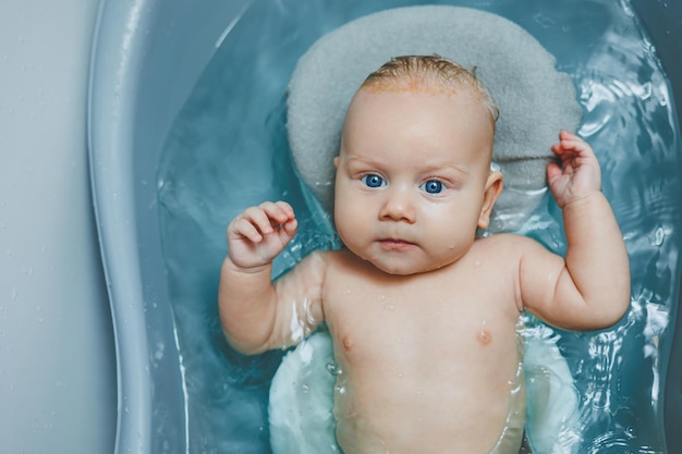 Igiene dei neonati e dei bambini Il bambino giace su un supporto e fa il bagno in una vasca da bagno Fare il bagno di un neonato in un bagno