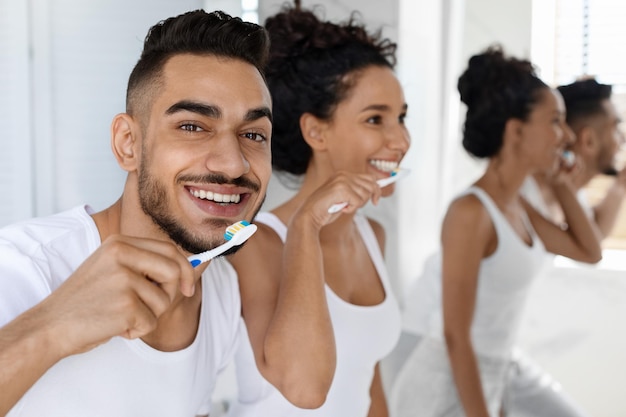 Igiene dentale felice giovane arabo e donna che si lavano i denti in bagno