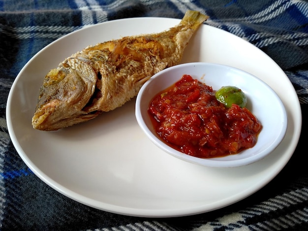 Ikan Goreng o pesce fritto con piccante su un piatto Cibo culinario tradizionale indonesiano