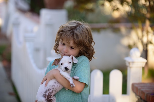 Il bambino abbraccia amorevolmente il suo cane da compagnia bambini carini che giocano con il cane misto chihuahua sdraiato sulla legge del cortile