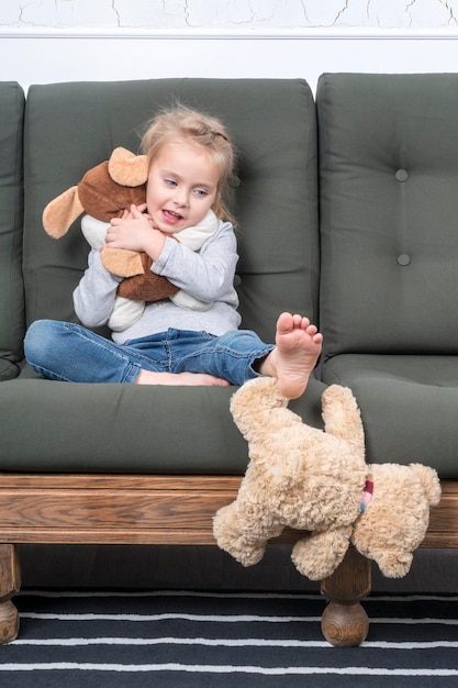 il bambino abbraccia il suo giocattolo preferito mentre spinge via l'orsacchiotto non amato con il piede