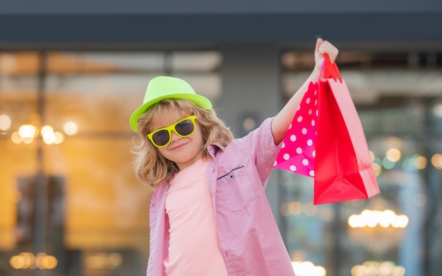 Il bambino acquirente si diverte a fare shopping moda bambino con la borsa della spesa piccolo bambino acquirente all'aperto