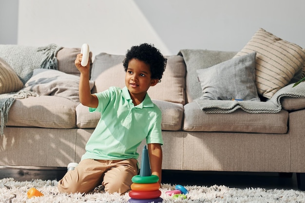 Il bambino afroamericano gioca con i giocattoli al chiuso vicino al letto di casa