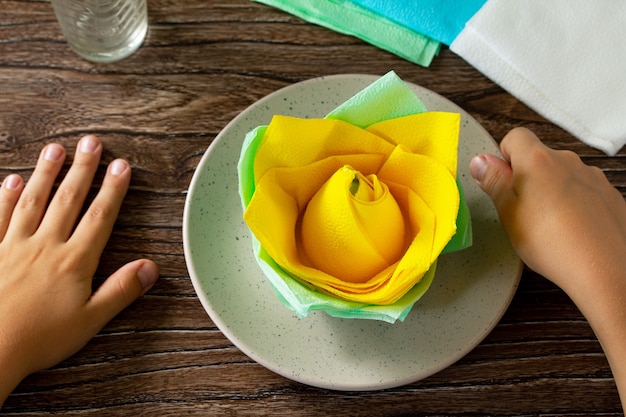 Il bambino aggiunge un fiore dai tovaglioli Tavola festiva Fatto a mano