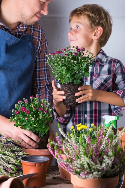Il bambino aiuta il padre a piantare fiori in famiglia a casa