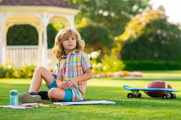 Il bambino all'aperto gioca e disegna opere d'arte artigianali compiti scuola intelligente ragazzo che fa i compiti scrivendo sulla copia bo