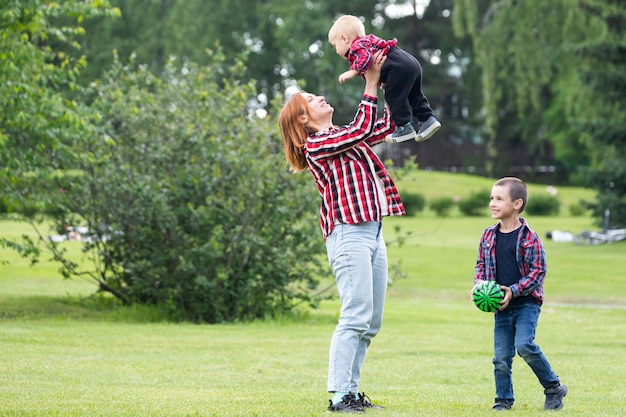 Il bambino allegro sveglio del fratello di due ragazzi con la madre gioca all'aperto nel parco