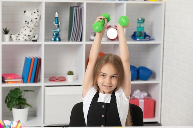 Il bambino allegro tiene i bilancieri nell'aula scolastica