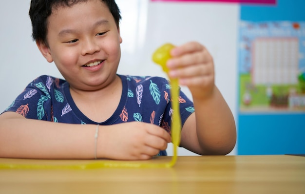 Il bambino asiatico tira la melma sul tavolo