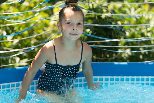 Il bambino bagnato si gode la soleggiata giornata estiva nuotando nel tempo libero della piscina all'aperto