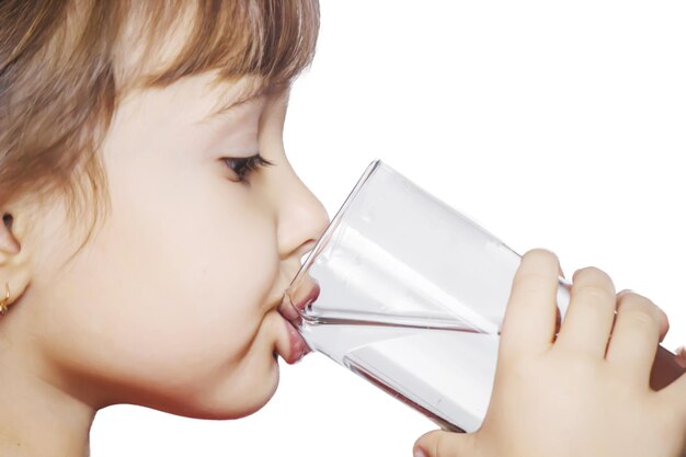 Il bambino beve acqua da un bicchiere di isolato Fuoco selettivo