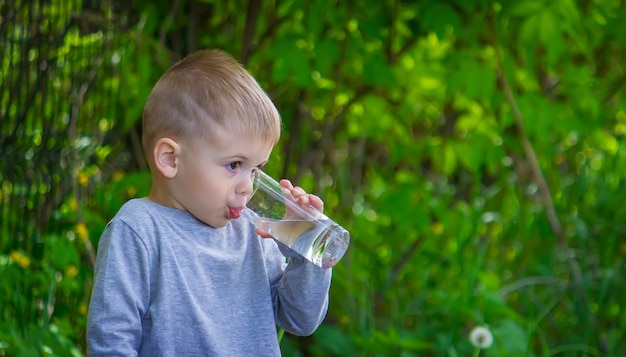 Il bambino beve acqua pulita in estate