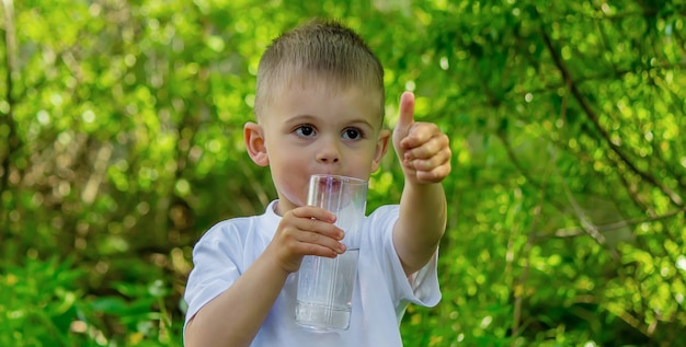 Il bambino beve acqua pulita in estate