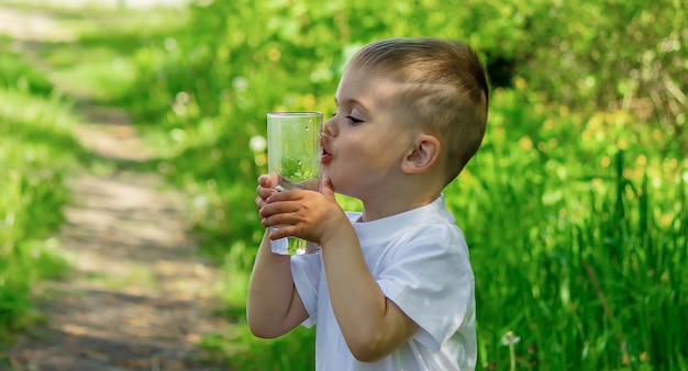 Il bambino beve acqua pulita in estate